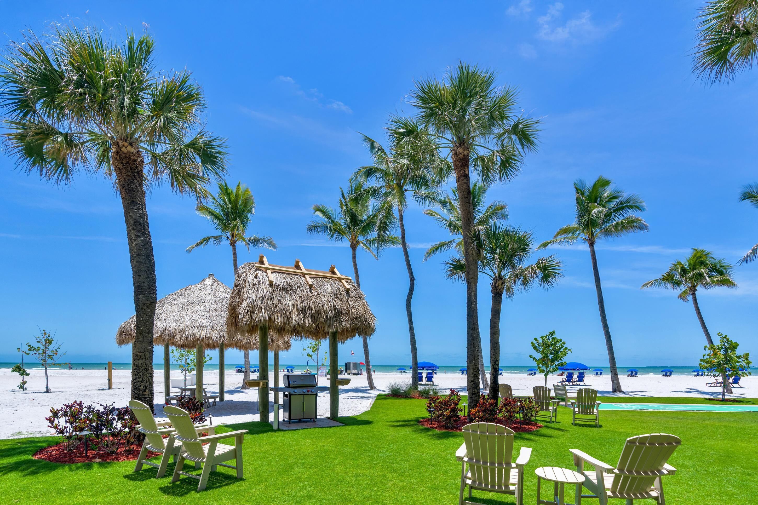 A beachside resort with thatched umbrellas, palm trees, and outdoor seating.