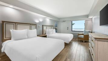 Une chambre d’hôtel avec deux lits, un bureau, une chaise et une vue sur l’océan.