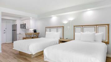 A hotel room with two beds, a kitchenette, and a wooden floor.