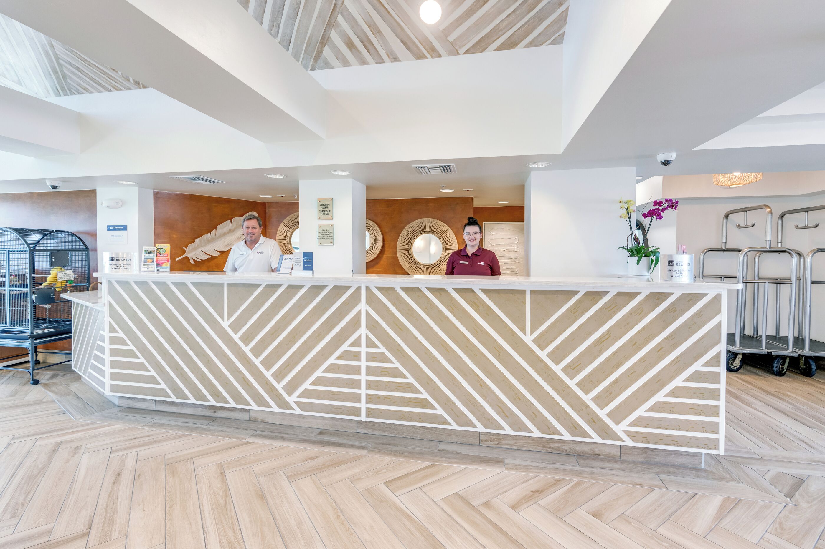 A reception desk with geometric patterns, a high ceiling with wooden beams, and a modern interior design.