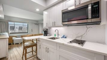 A modern kitchen with white cabinetry, a built-in microwave, and a sink.