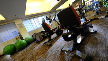 A gym with exercise equipment, a water dispenser, and exercise balls.