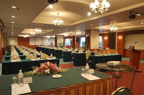 A conference room with multiple tables, chairs, and a podium.