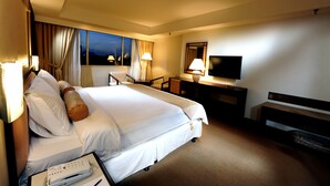 A hotel room with a bed, desk, TV, and curtains. - Grand Margherita Hotel (Kuching)