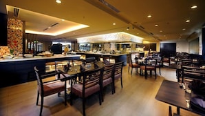 A restaurant with a central island, multiple dining tables, and chairs. - Grand Margherita Hotel (Kuching)