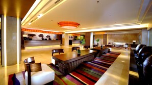 A modern hotel lobby with a reception desk, seating area, and a large window. - Grand Margherita Hotel (Kuching)