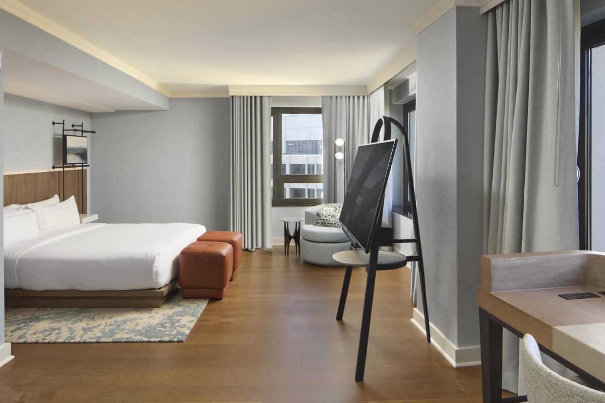 Una habitación de hotel con una cama, un escritorio, una silla, un televisor y una ventana.