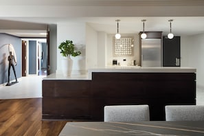 A modern kitchen with a dark wood island, a white vase with a plant, and a built-in refrigerator. - Washington Hilton (Washington)