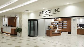 A clean, modern interior of a District Line café and market with a marble floor, wooden counters, and a variety of products on display.