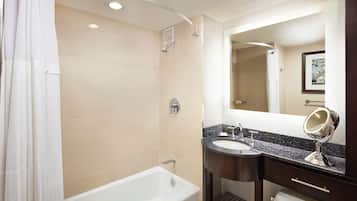 Un baño moderno con bañera, ducha, tocador con lavabo y espejo, y un inodoro.