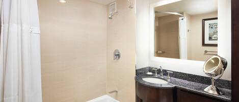 A modern bathroom with a bathtub, a shower, a vanity with a sink and mirror, and a toilet.
