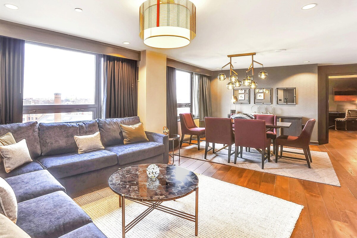 A modern living room with a sofa, a glass coffee table, and a dining area with chairs and a table.