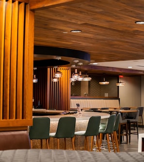 Un restaurante con techo de madera, mesas redondas y sillas tapizadas en verde.