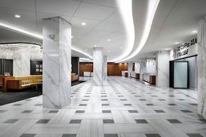 A modern hotel lobby with a marble floor, a reception desk, and a sign for 'The Coffee Bean & Tea Leaf'. - Washington Hilton (Washington)