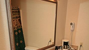 A bathroom with a granite countertop sink, a large mirror, a coffee maker, and a towel rack.