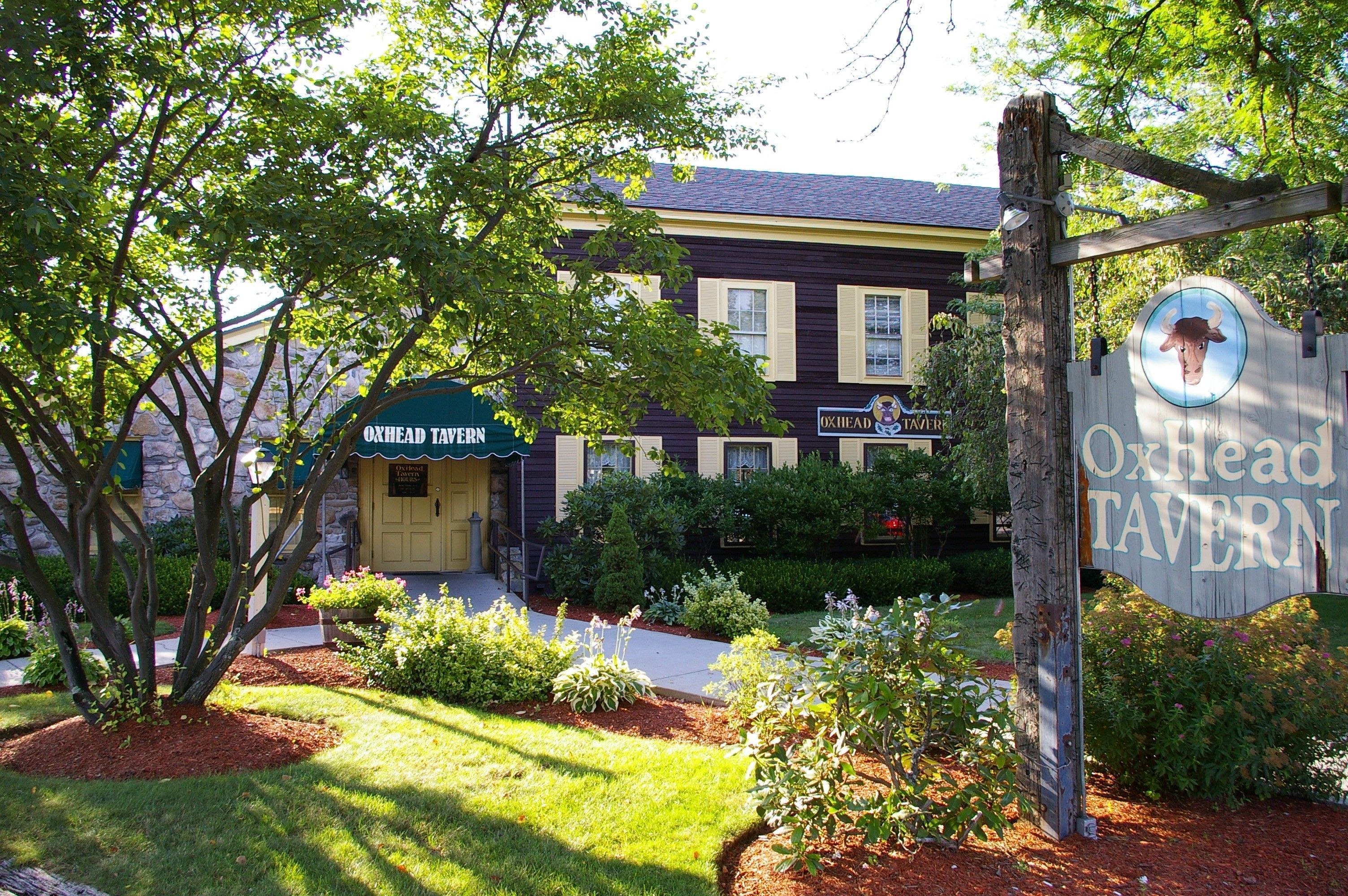 A building with a sign reading "Oxhead Tavern" and a wooden sign with a bull's head.