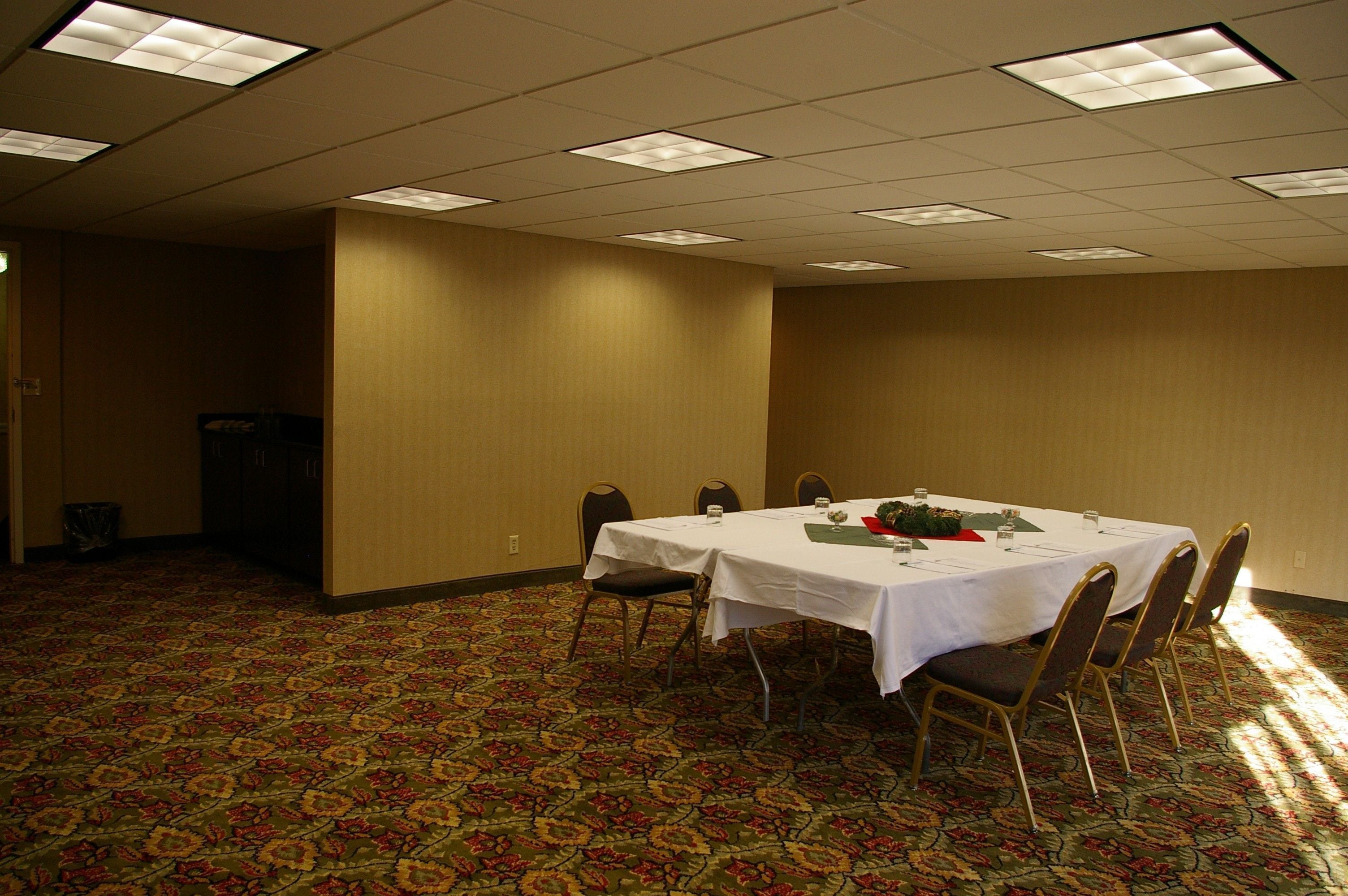 A conference room with a large table, chairs, and a carpeted floor.