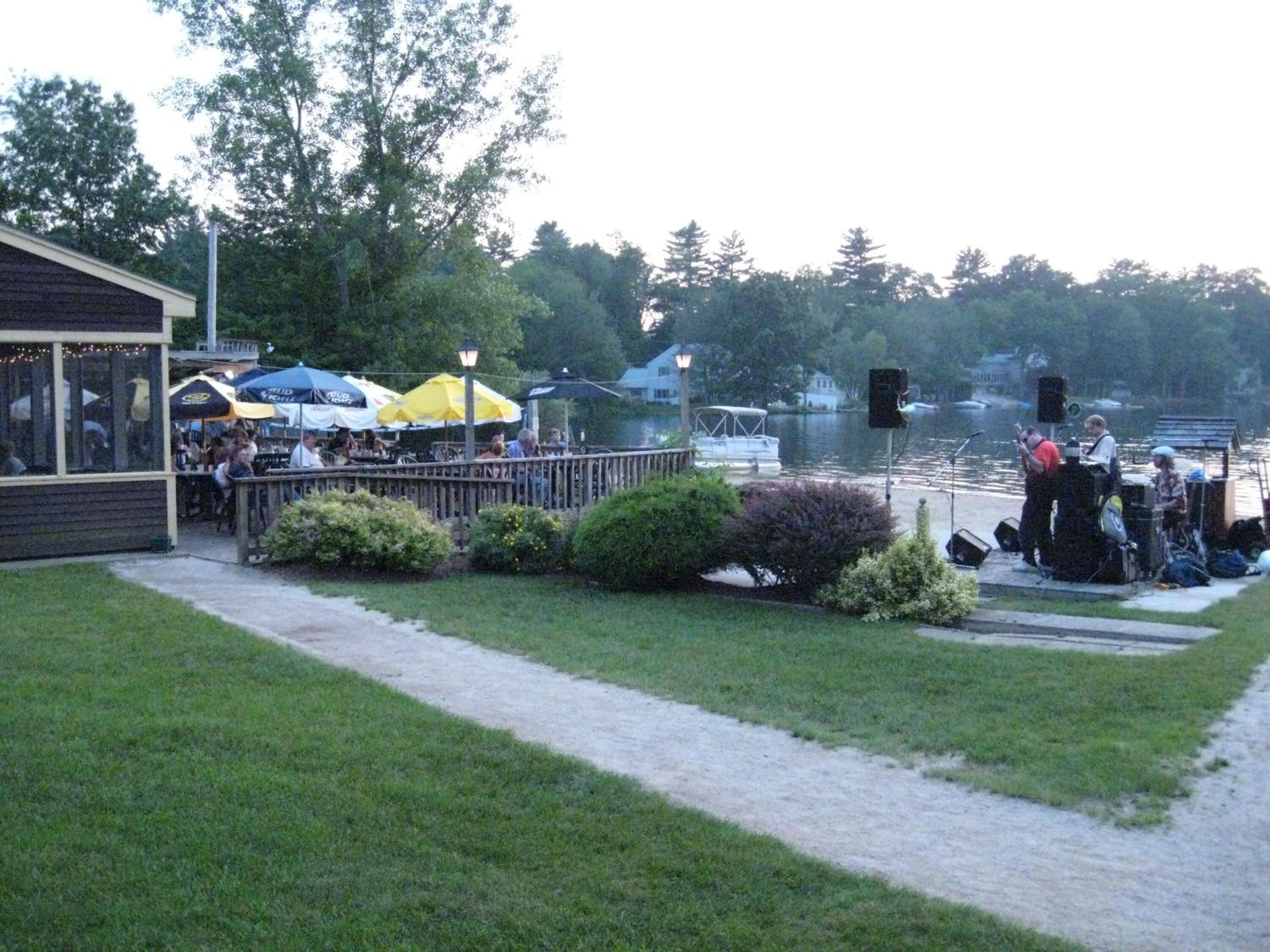 A lakeside restaurant with outdoor seating and a dock.