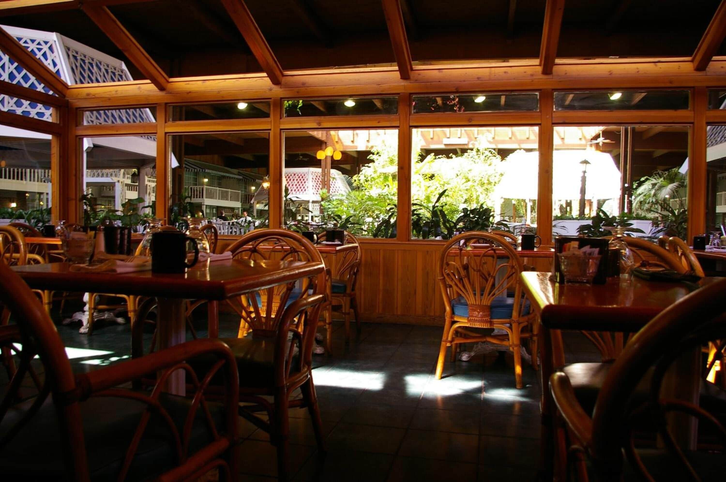 An indoor restaurant with wooden furniture and large windows.