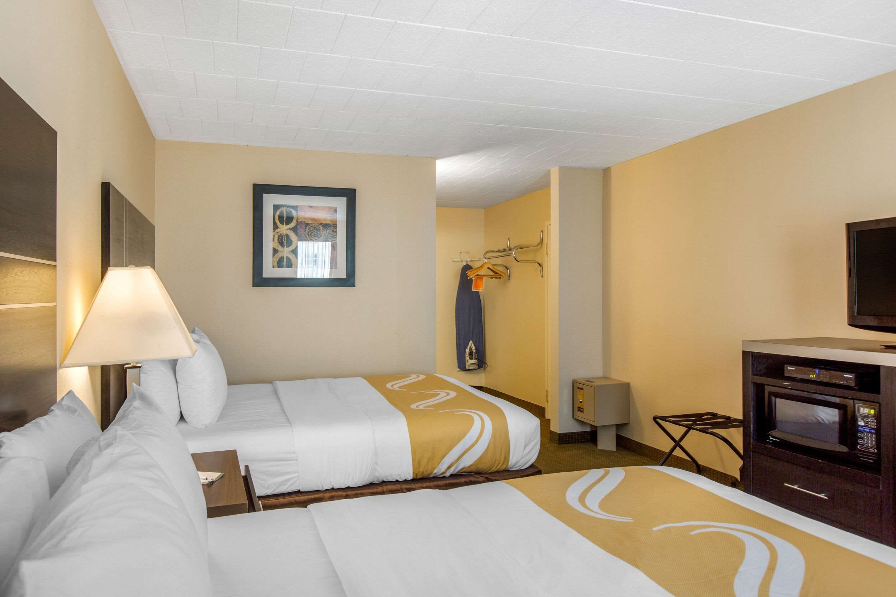 Une chambre d’hôtel avec deux lits, une télévision, un four  à micro-ondes et un porte-manteau.