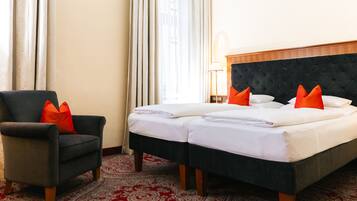 A hotel room with a bed, two pillows, a chair, a lamp, and a patterned carpet.