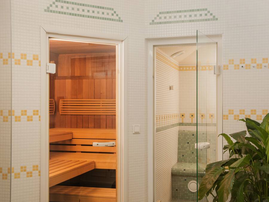 A sauna room with wooden benches and a glass door leading to a shower area.