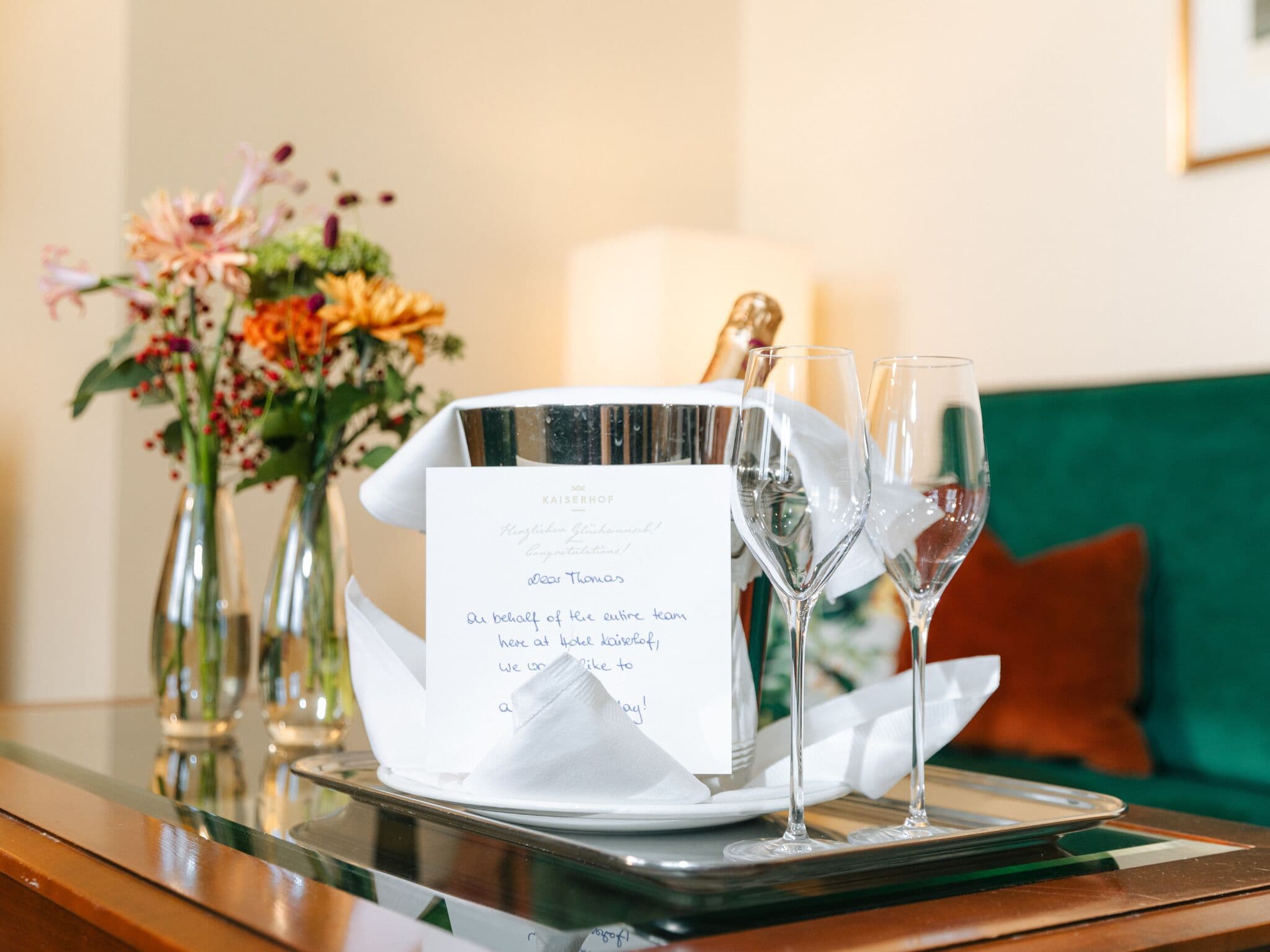 A table with a menu, two wine glasses, and a vase with flowers.