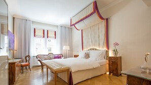 Una habitación de hotel con una cama grande, un banco de madera, un escritorio y una silla.