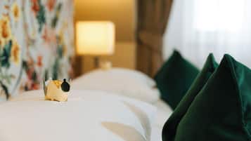 A neatly made bed with a decorative object on the left side, a lamp in the background, and green pillows on the right.