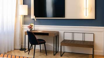 Habitación de hotel con escritorio, silla y televisor montado en la pared.