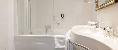 Un baño moderno con ducha de vidrio, un lavabo blanco con tocador y un espejo con marco decorativo.