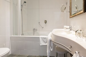 Un bagno moderno con doccia vetrata, un lavabo bianco con mobile contenitore e uno specchio con cornice decorativa.