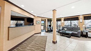 Eine Hotelhalle mit Empfangstresen, Sitzgelegenheiten und großen Fenstern.