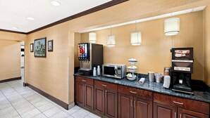 Ein Hotel-Empfangsbereich mit Kaffee-Ecke, darunter eine Kaffeemaschine, eine Mikrowelle und Getränkespender.