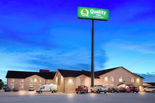 Un Quality Inn de Choice Hotels con fachada de ladrillo, varios espacios de estacionamiento y un letrero verde llamativo.