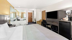 Ein Hotelzimmer mit einem großen Bett, einem Schreibtisch, einem Fernseher, einer Kaffeemaschine und einem Minikühlschrank.