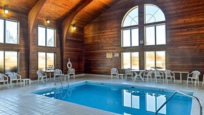 Ein Hallenbad mit Fliesenboden, Holzvertäfelung und großen Fenstern.