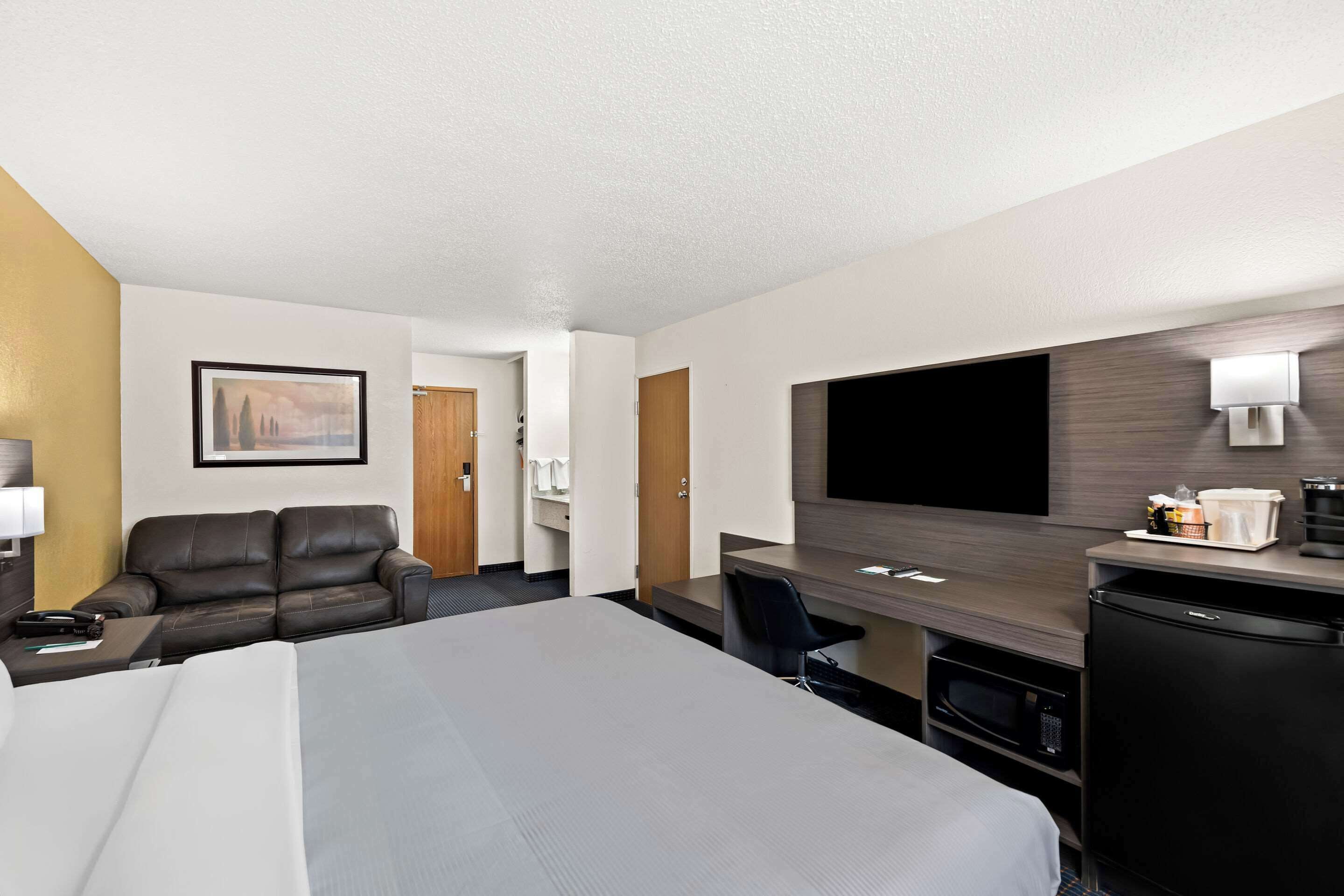 Ein Hotelzimmer mit Bett, Schreibtisch, Stuhl, Fernseher und einer Kaffeemaschine.