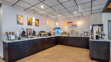 A modern kitchen area with a breakfast bar, coffee machines, and a sign that reads "RISE & Shine."