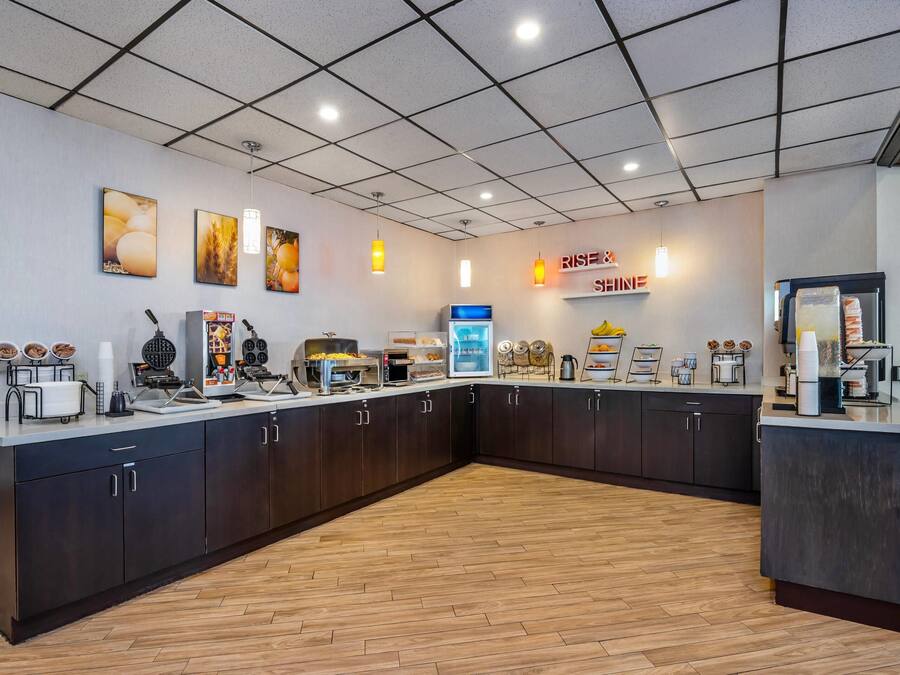 A modern kitchen area with a breakfast bar, coffee machines, and a sign that reads "RISE & Shine."