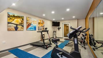 Un gimnasio con cintas de correr, bicicletas estáticas y máquinas de pesas.