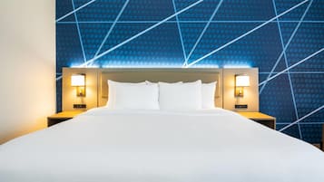 A hotel room with a large bed, two bedside tables with lamps, and a blue patterned wall.