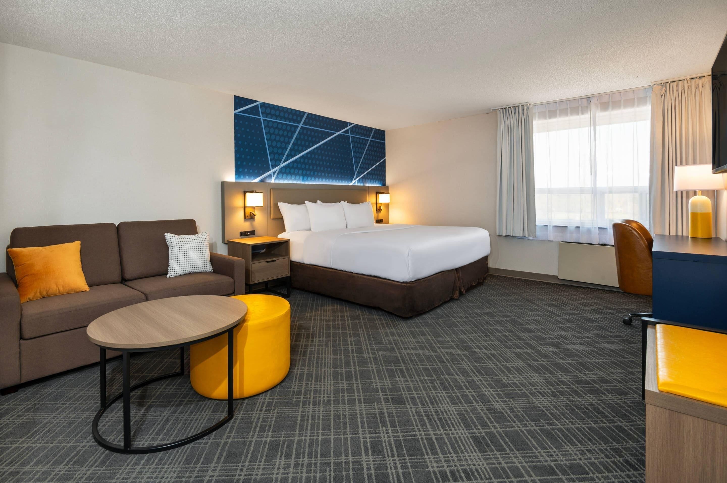Una habitación de hotel con cama, sofá, escritorio, silla y una pequeña mesa.