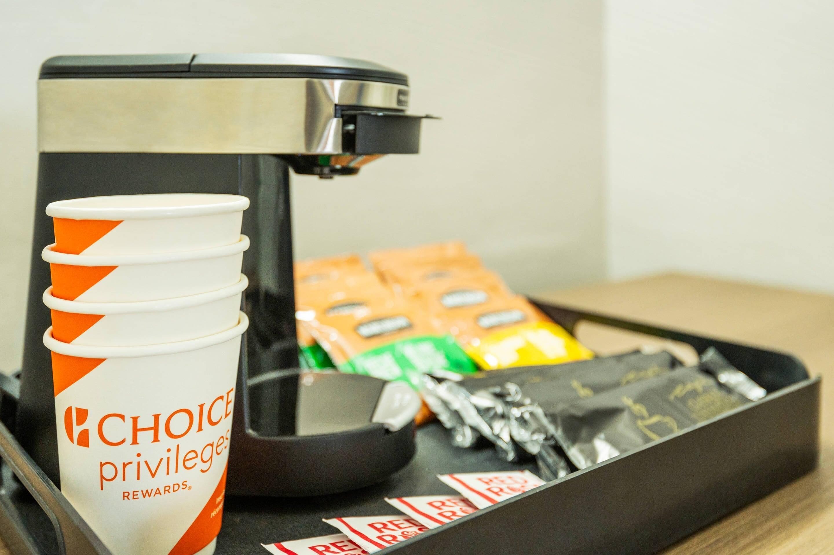 A coffee machine, a tray with coffee cups and coffee pods, and a small bowl.