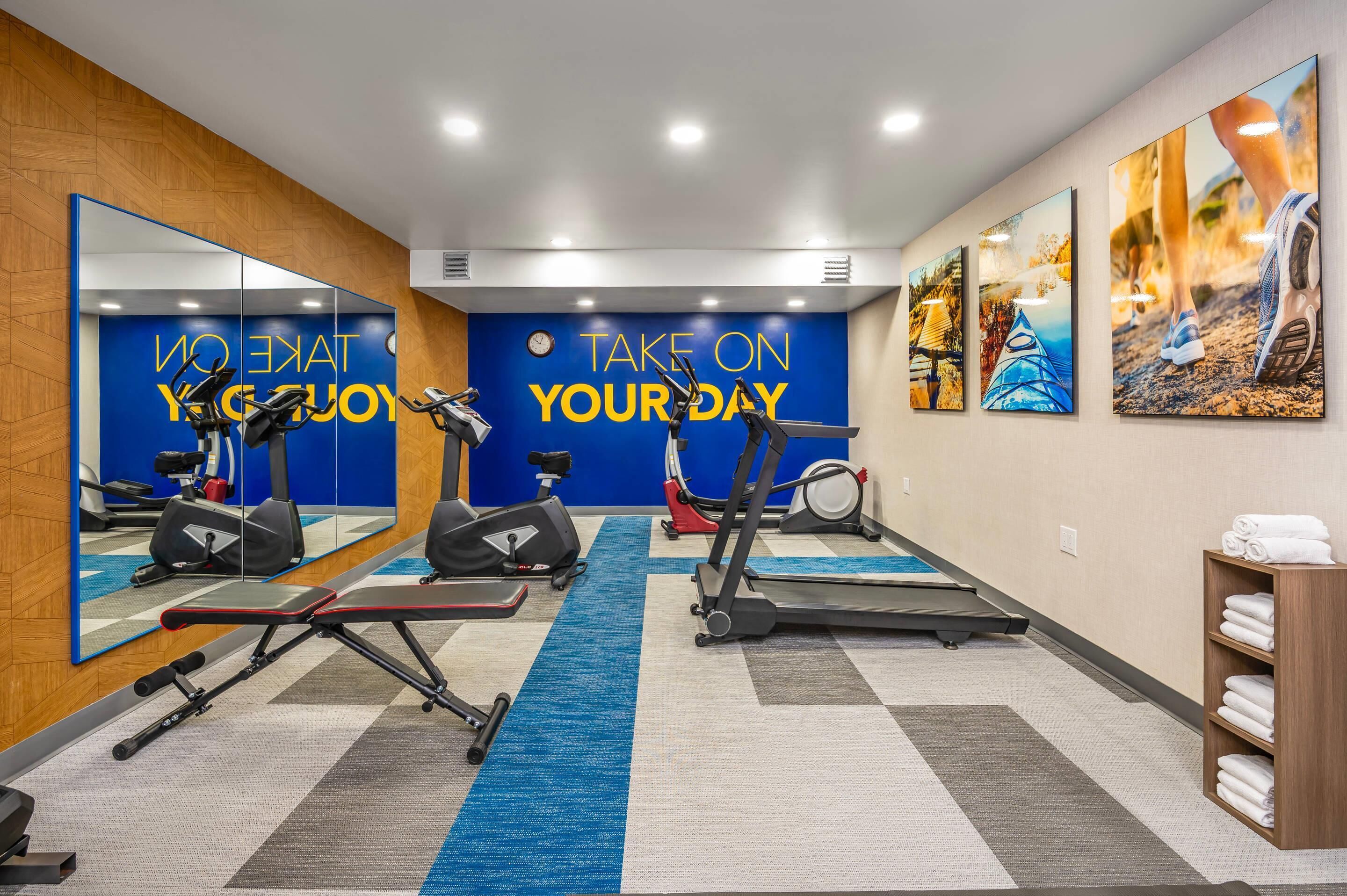 A gym with exercise equipment, motivational wall text, and artwork.