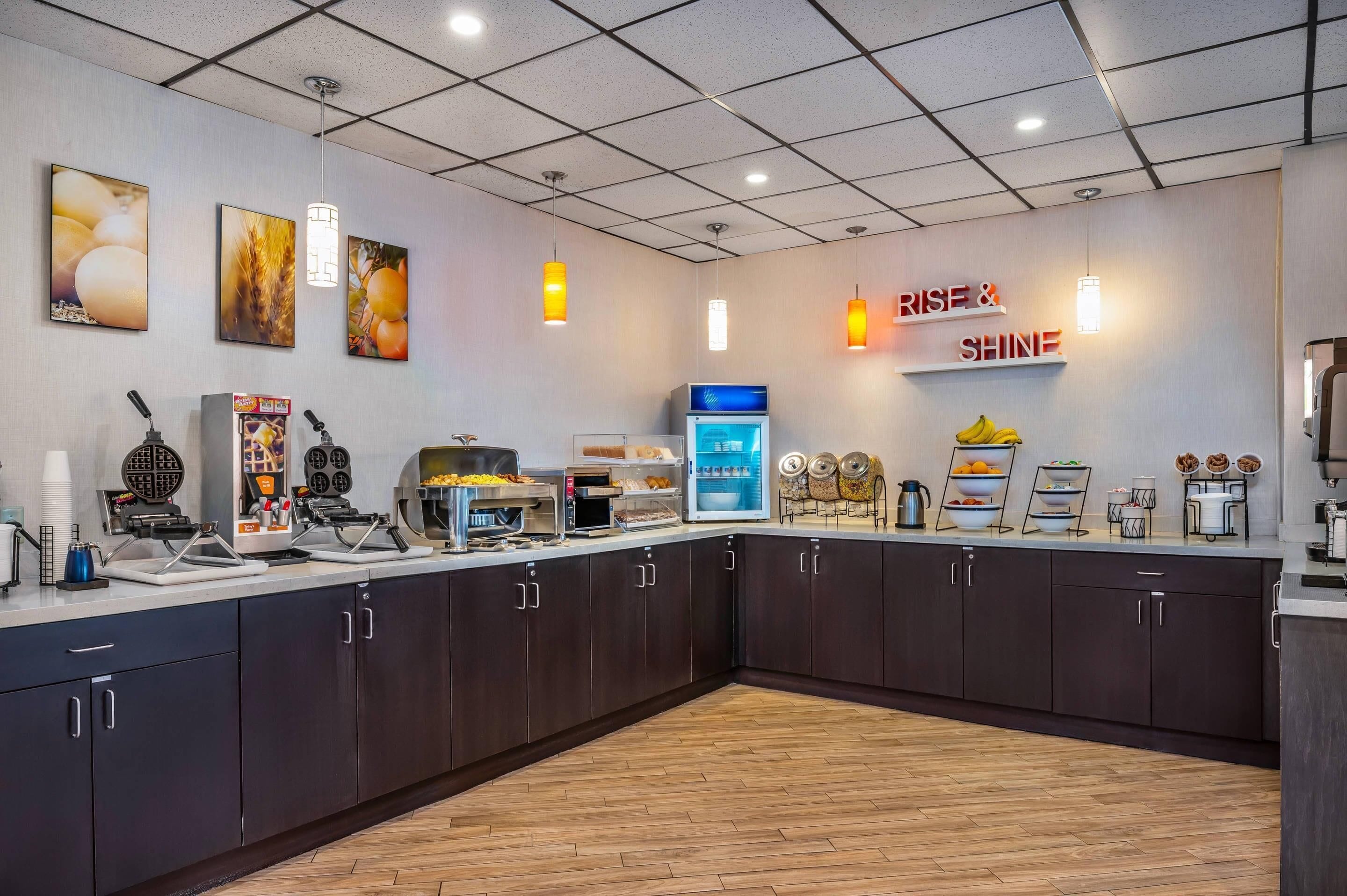 Une cuisine moderne équipée d’un bar pour prendre le petit-déjeuner, d’un appareil à gaufres, d’un coin café et d’un écran numérique affichant le menu.