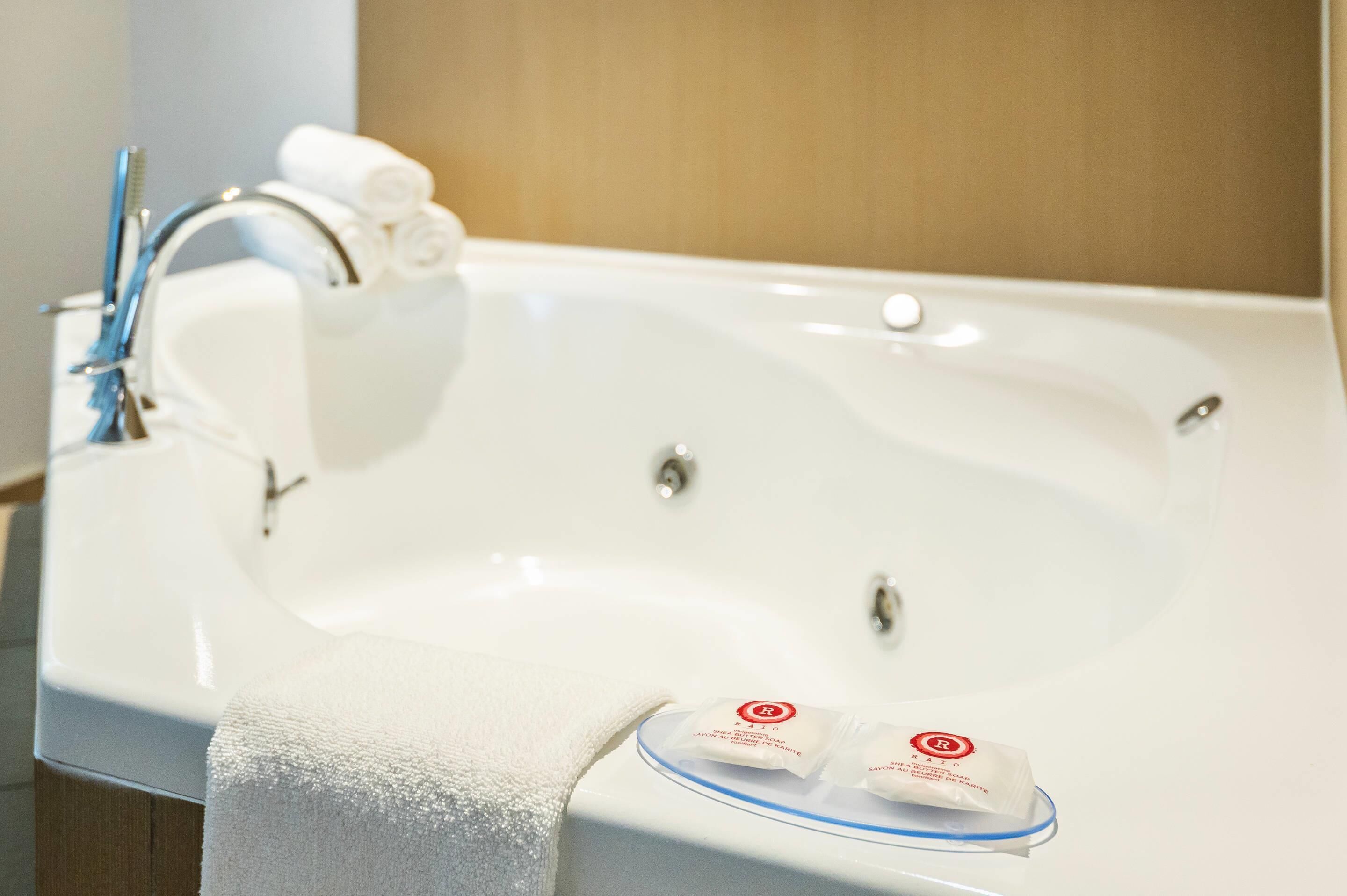 A white bathtub with a blue rim, a white towel, and two soap packets.