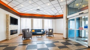 A spacious lobby with a checkered floor, a stone fireplace, a flat-screen TV, and a seating area with a sofa and chairs. - Comfort Inn & Suites Barrie - Highway 400 (Barrie)