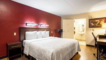 A hotel room with a bed, bedside tables, a desk, and a chair.