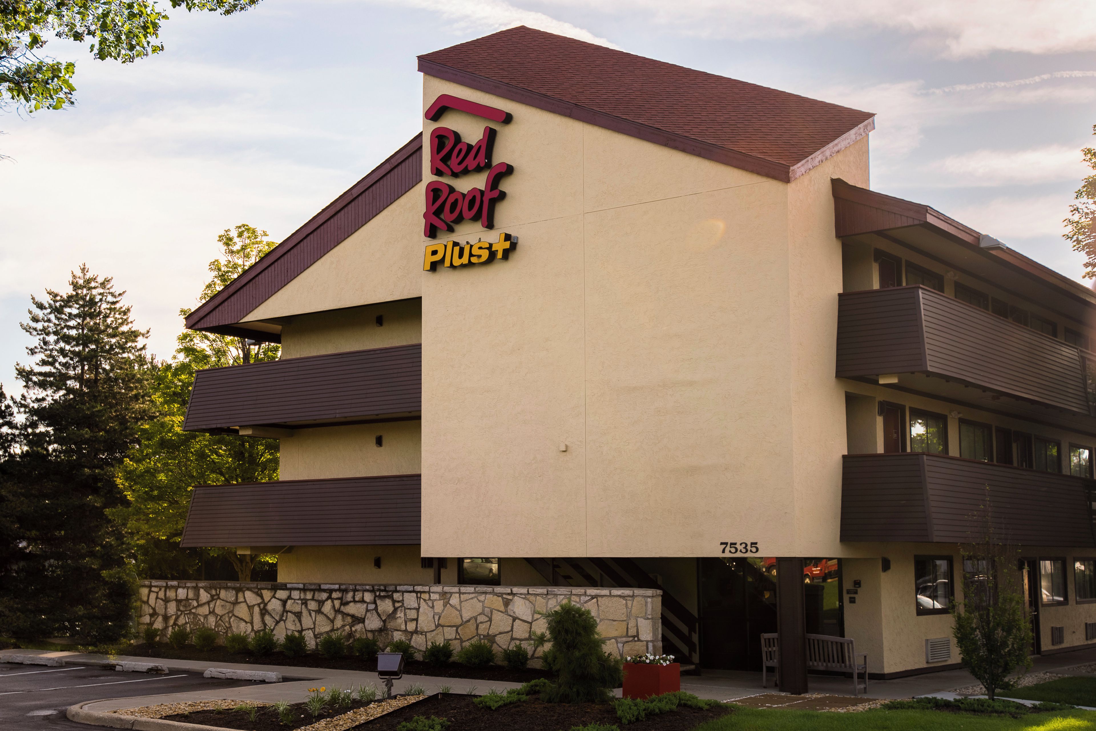 A multi-story hotel with a prominent sign reading 'Red Roof Plus'.